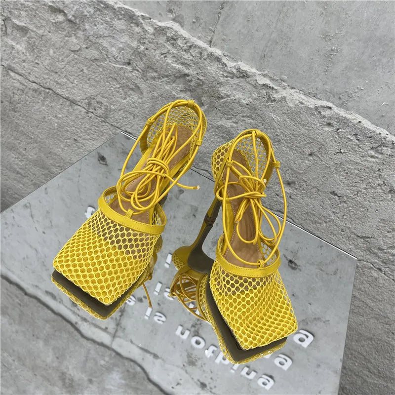 Yellow mesh high-heeled shoes on a gray surface