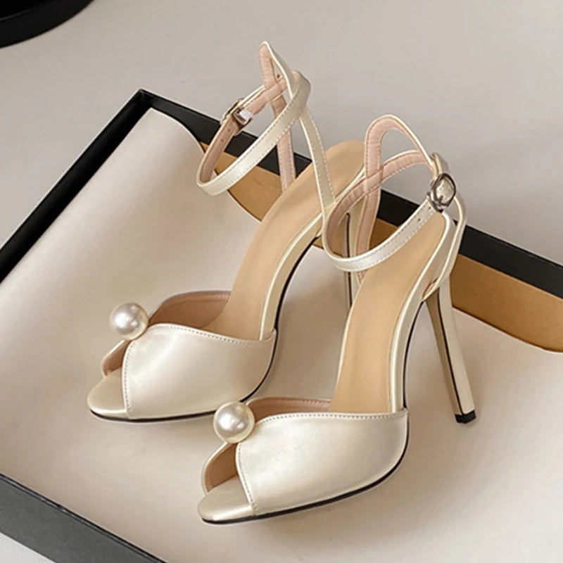 Beige high-heeled shoes with pearl embellishments on a light background