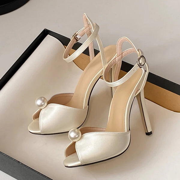 Beige high-heeled shoes with pearl embellishments on a light background