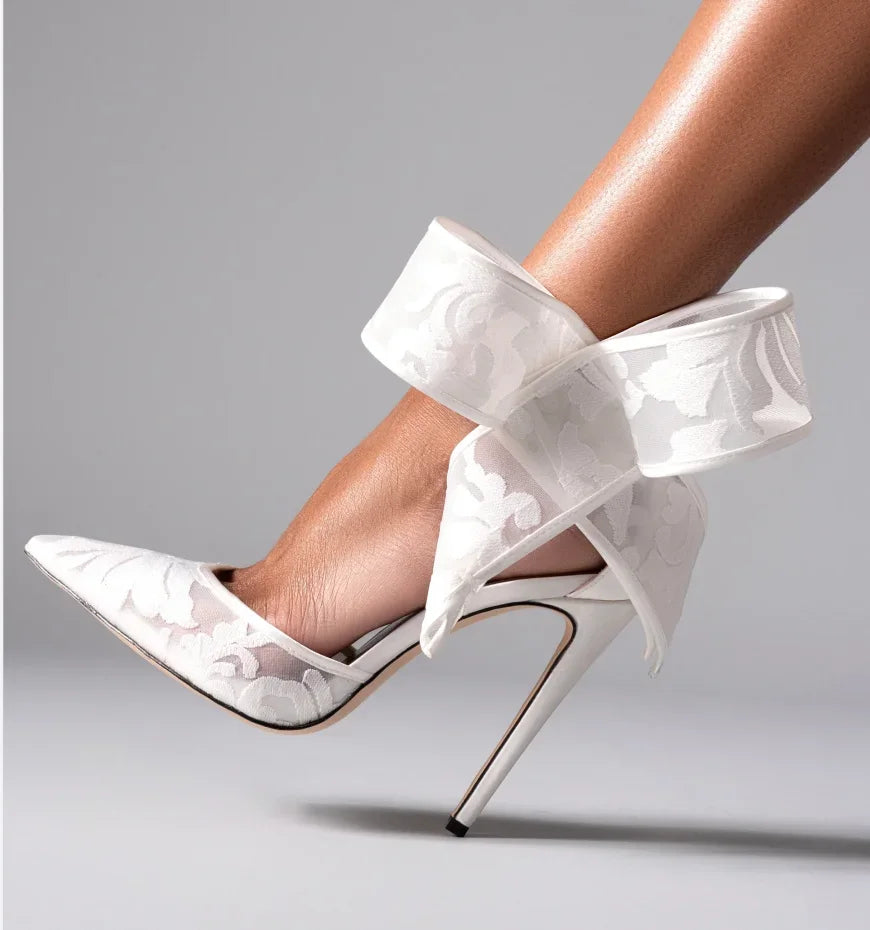 White lace high-heeled shoes on a gray background