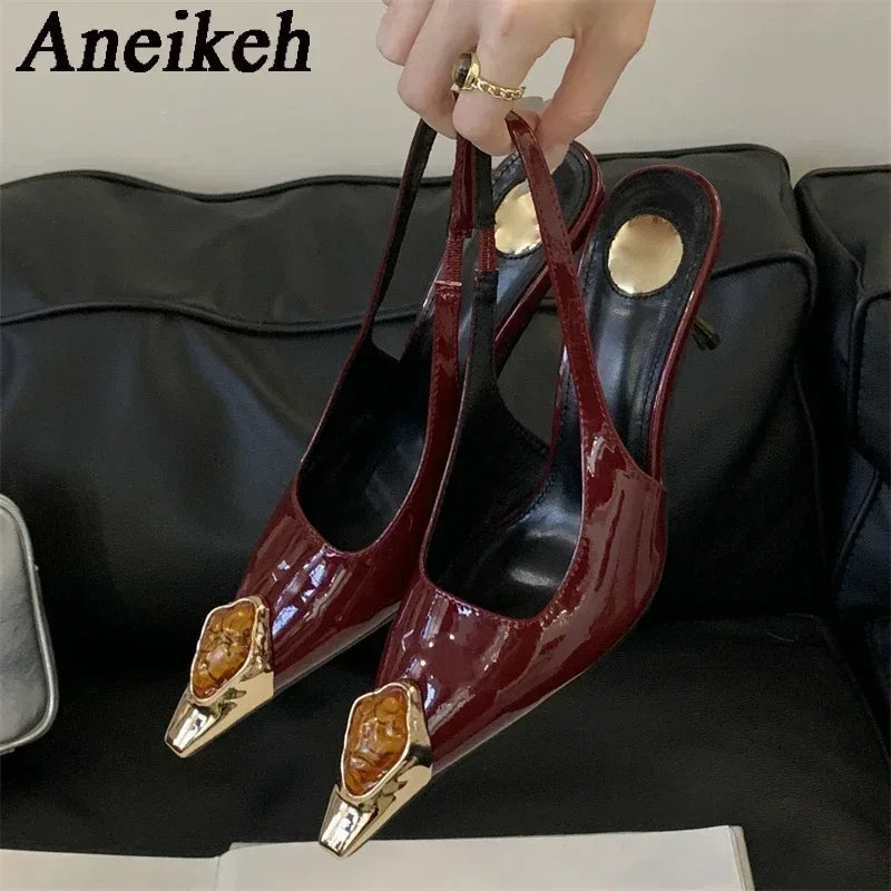 Red high-heeled shoes with gold tips held by a hand on a black background