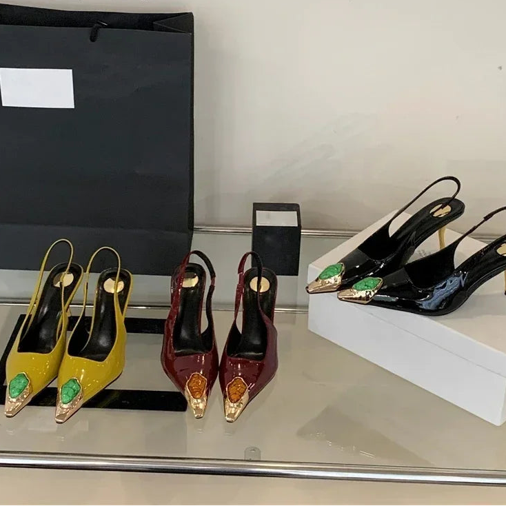 Pair of yellow and maroon high-heeled shoes with decorative elements on a reflective surface, branded 'Aneikeh'.
