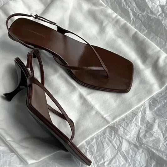 Pair of brown high-heeled sandals on a textured white surface