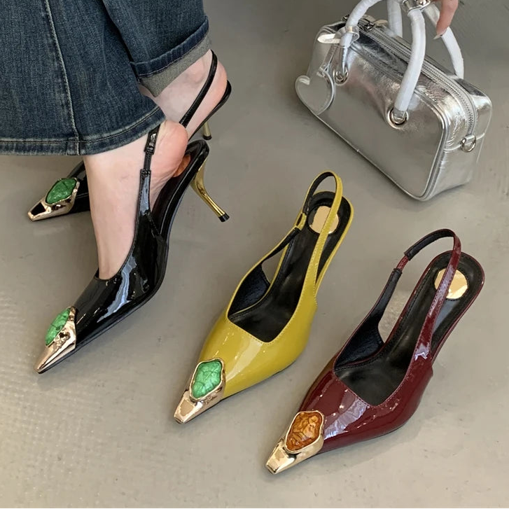 Black, yellow, and red high-heeled shoes with decorative elements on a neutral background.