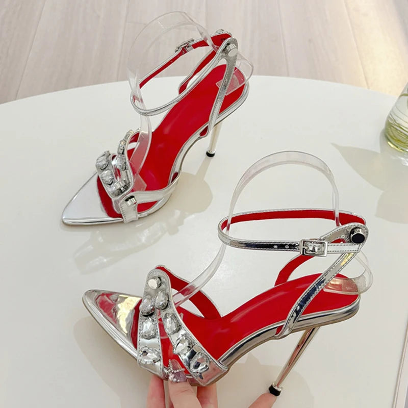 Red high-heeled shoes with clear straps and silver accents on a white surface.