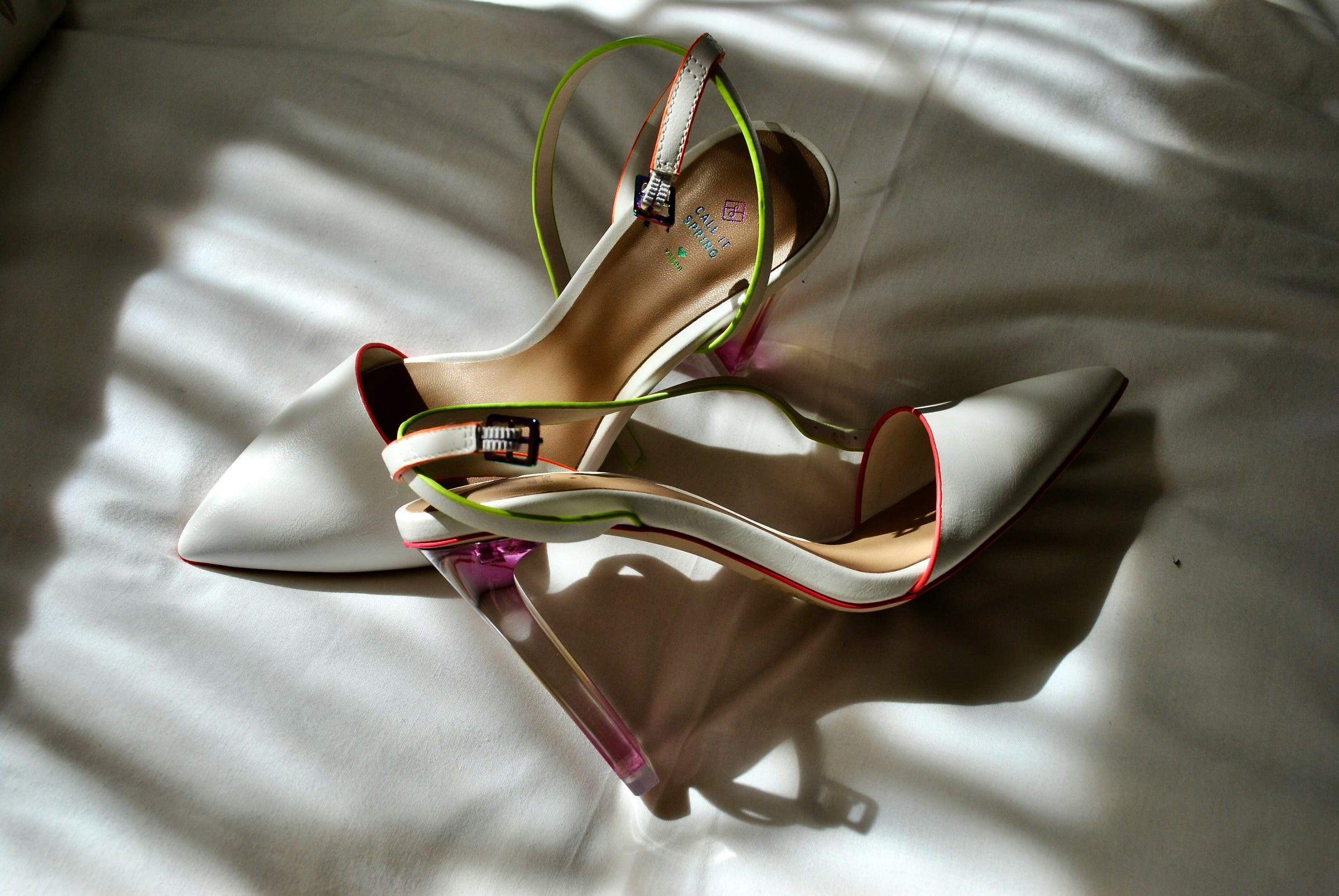 Pair of high-heeled shoes with colorful interior on a textured surface